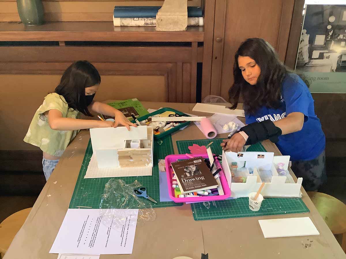 Two campers work on separate models at one of Frank Lloyd Wright’s drafting tables in the Studio