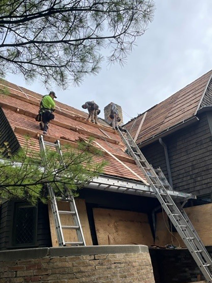 Workers installing new shingles on the home.