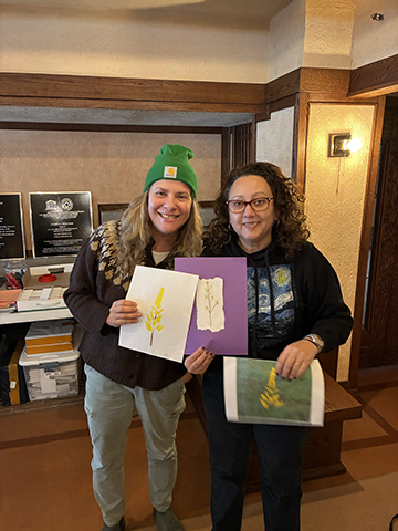 Two educators hold up their abstract drawings of a prairie plant, inspired by Wright’s art glass windows.